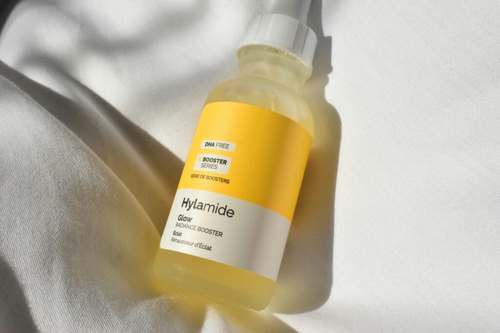 A close-up image of the Hylamide Glow Radiance Booster skincare product on white fabric.