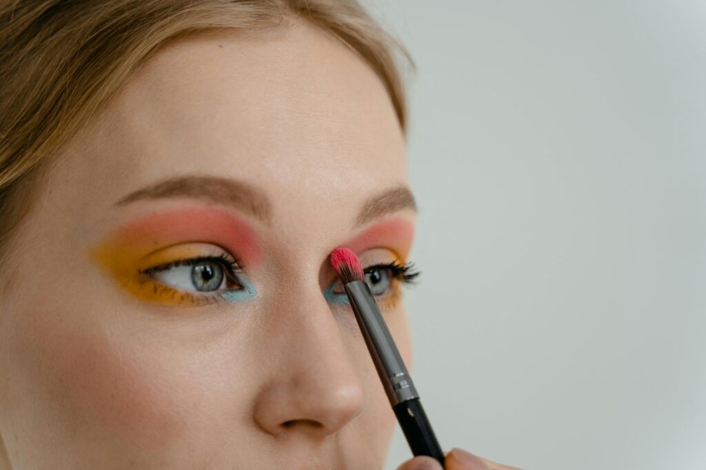 Vibrant eyeshadow application close-up with makeup brush on woman's eyelid.