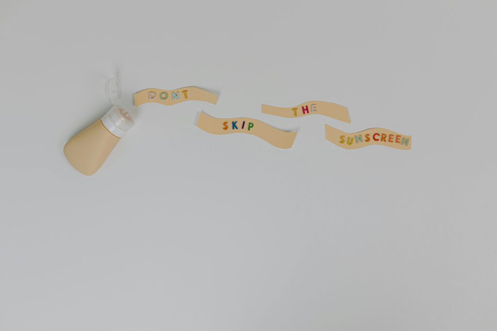Sunscreen bottle and creative text 'Don't Skip the Sunscreen' on white background, promoting skincare and cancer prevention.