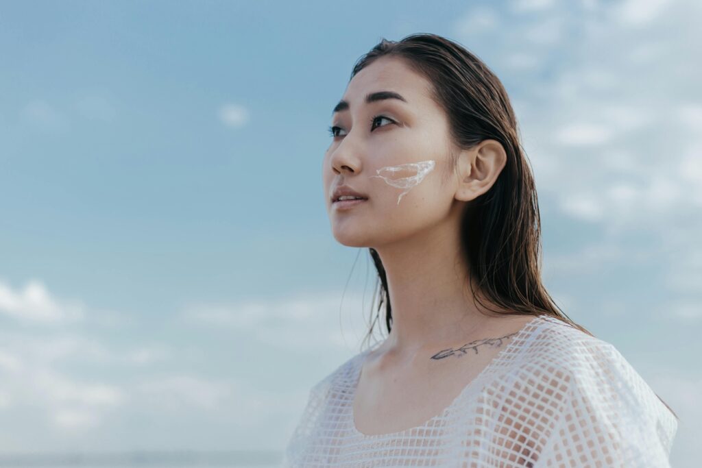 Portrait of a woman with skincare product on her face against a clear sky.